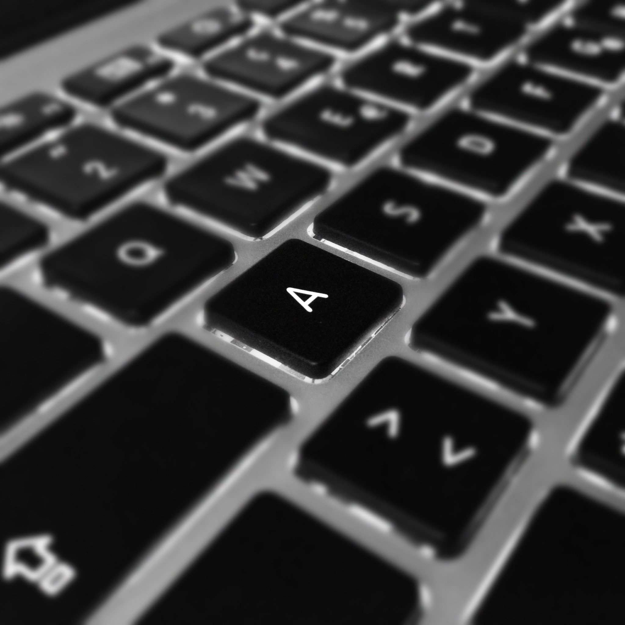 มือของนักพัฒนาพิมพ์โค้ดบนคีย์บอร์ด Artistic black and white close-up of a laptop keyboard