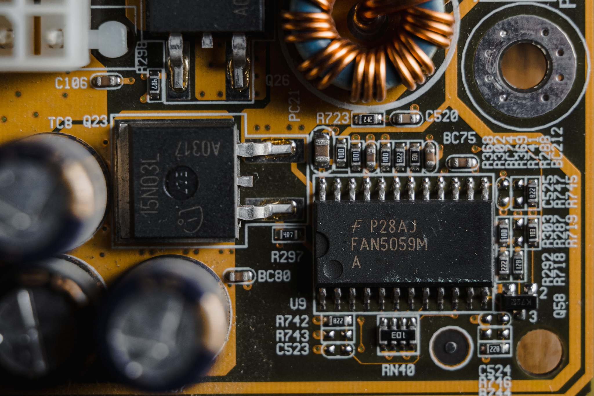 แผงวงจรอิเล็กทรอนิกส์และชิปบนโต๊ะทำงาน Detailed view of microchips and components on a motherboard circuit board.